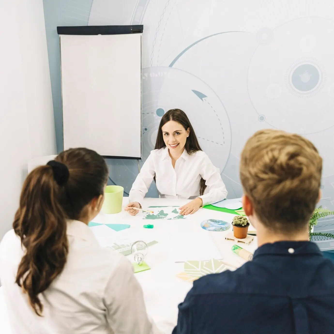 Деловые партнёры сидят перед улыбающейся женщиной-менеджером на рабочем месте.